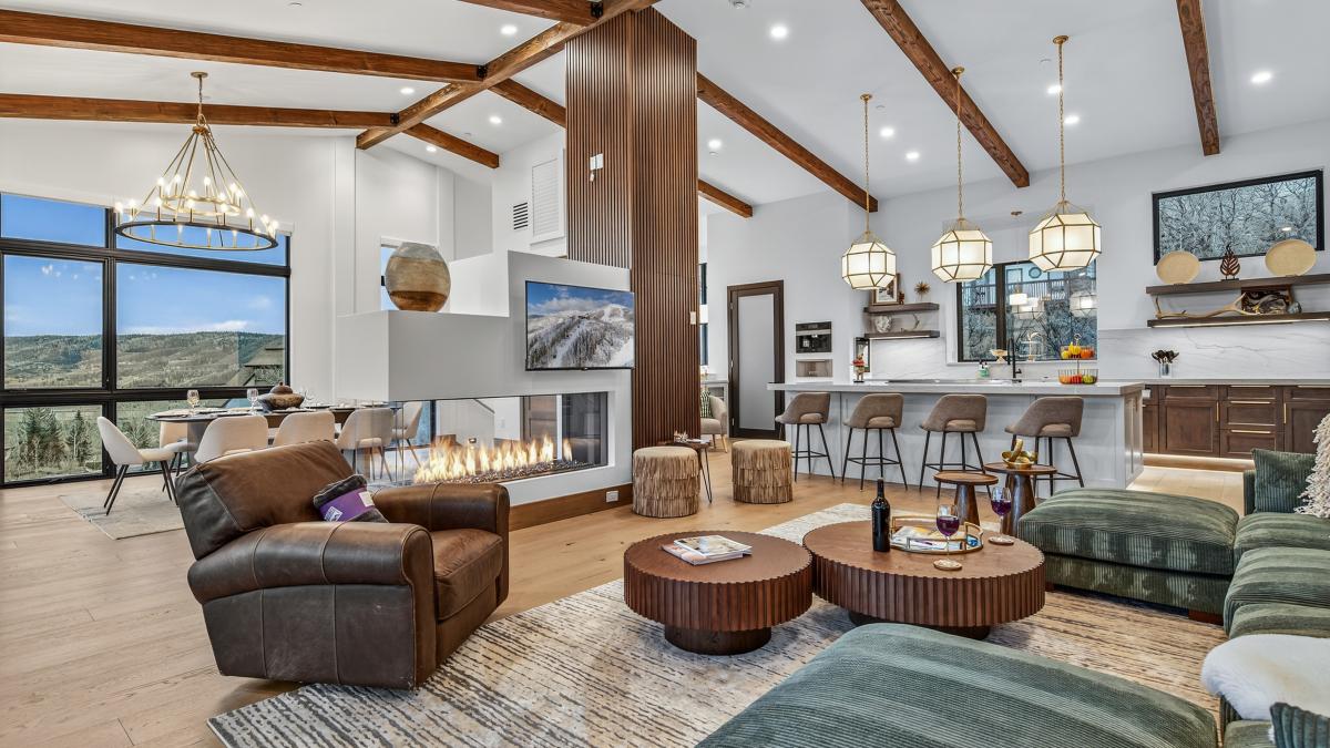 Unwind in this stunning open-concept living space where soaring wood beams frame your mountain retreat, complete with a cozy fireplace and chef's kitchen.