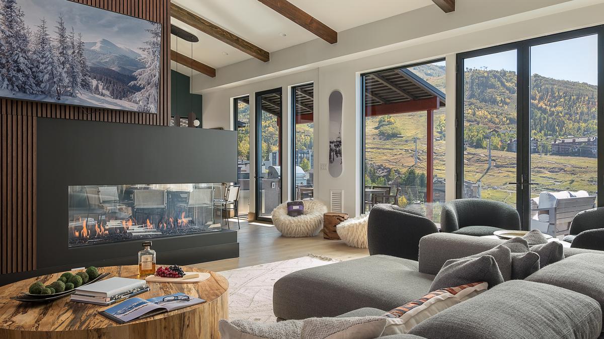 Unwind on plush sofas by the modern fireplace while soaking in breathtaking mountain views through floor-to-ceiling windows.