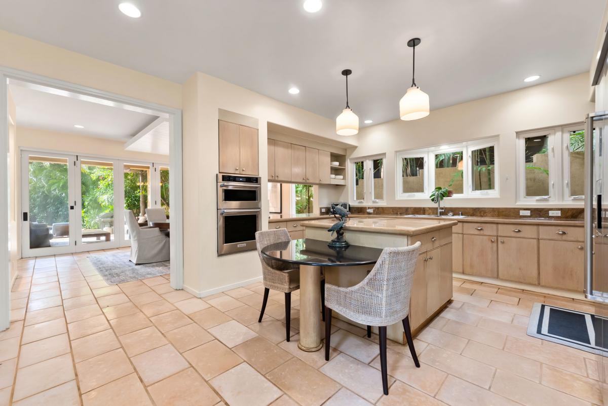 Your gourmet kitchen awaits with granite counters, stainless appliances, and island seating. Natural light fills the space through windows overlooking lush greenery.