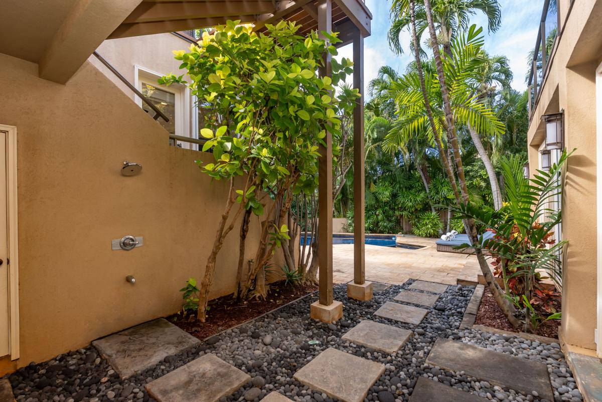 Step into your private tropical oasis where lush palms and tropical plants create a serene garden entrance leading to the sparkling pool.