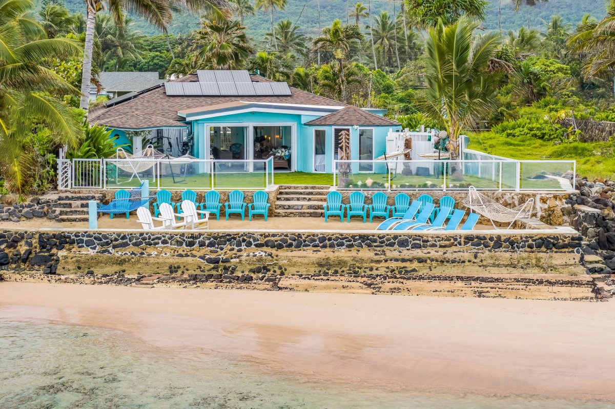 Take in a full view of your beachfront retreat from the water, showcasing expansive outdoor seating, oceanfront lawn space, and uninterrupted coastal scenery.