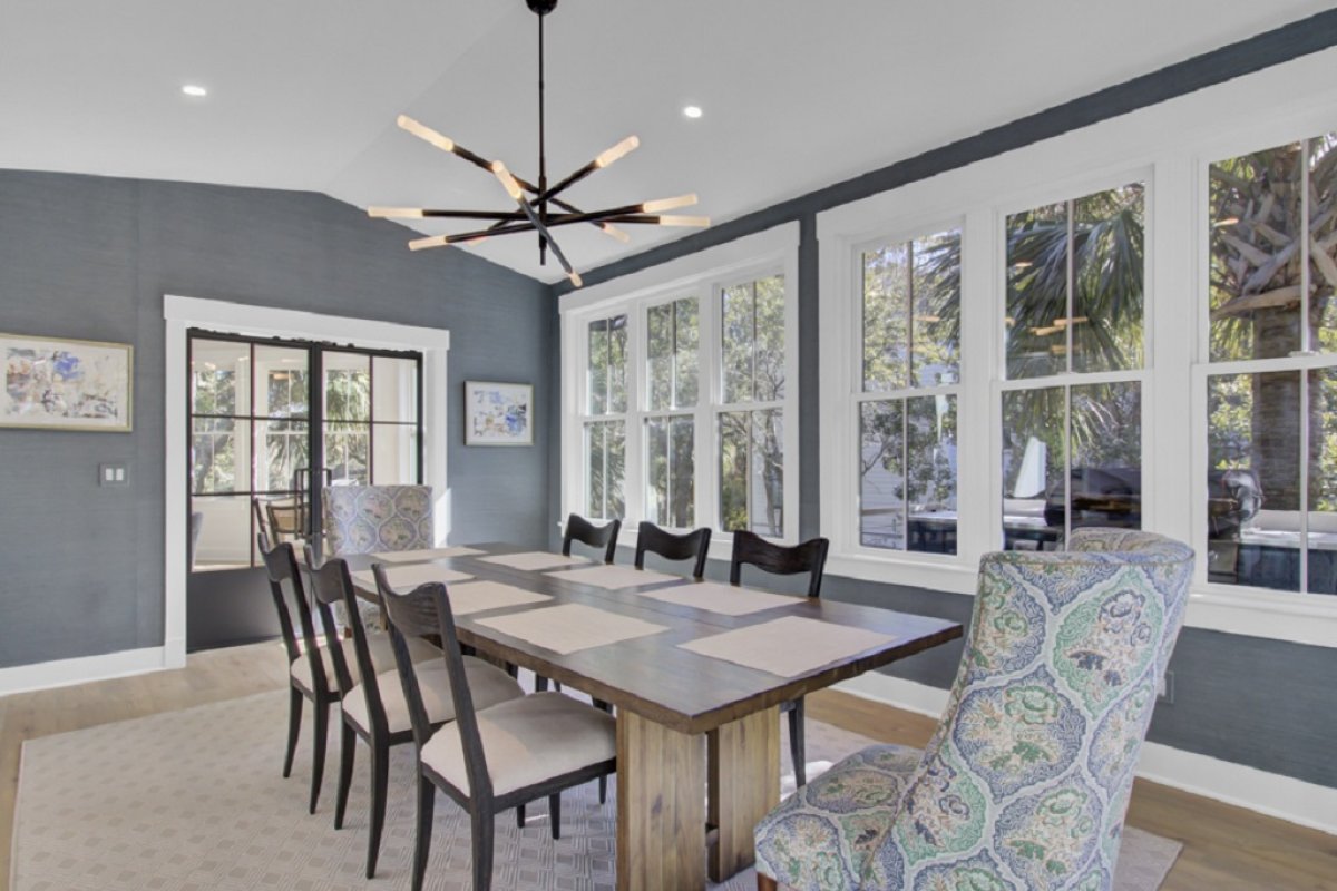 Surrounded by tall windows, this dining room feels bright, airy, and welcoming - Sleek wood table and patterned chairs balance modern design with relaxed charm - Perfect setting for sunny breakfasts or candlelit dinners