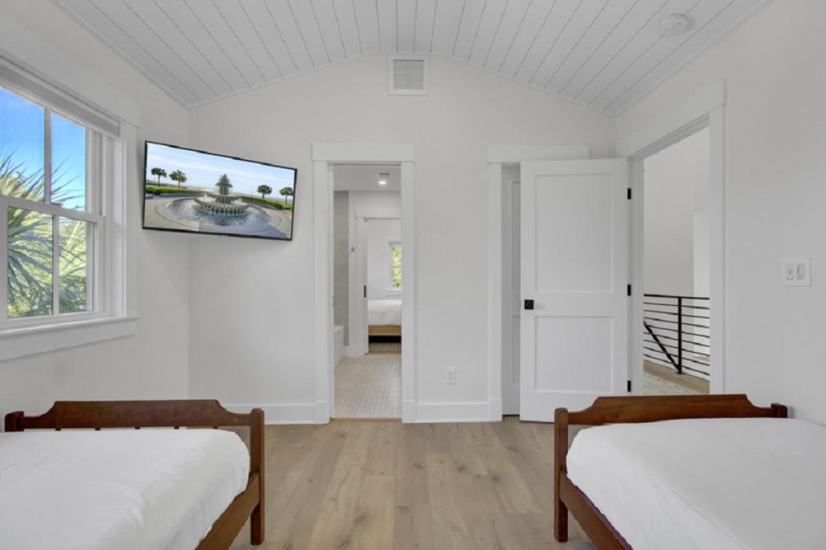 - Crisp and clean twin room with wood accents and vaulted ceiling detail - Wall mounted smart TV adds entertainment without cluttering the space - Direct access to hallway and upstairs rooms keeps everything connected
