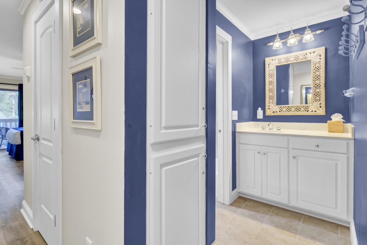 Step into your stylish bathroom featuring crisp white cabinetry, elegant blue walls, and a statement gold mirror that adds warmth to your daily routine.