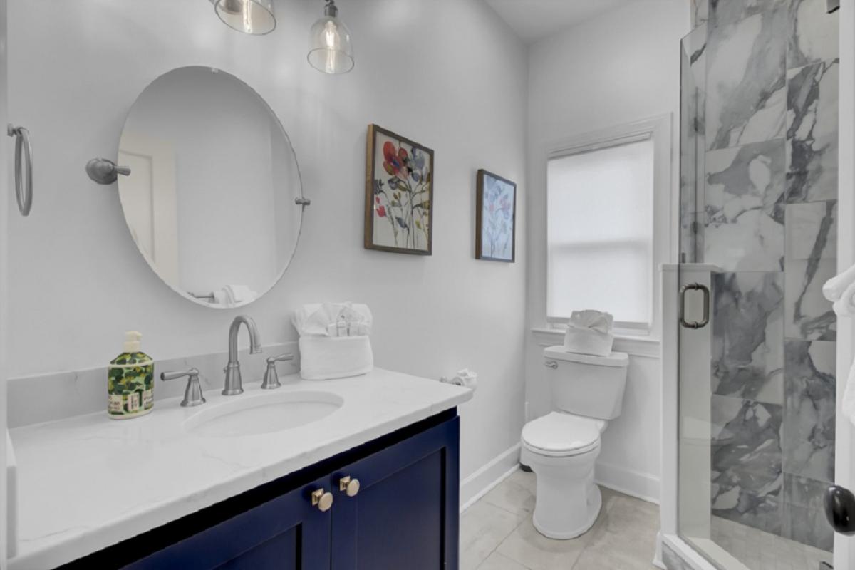 - Bold navy vanity and gold accents give this bathroom a luxe, magazine worthy feel - Framed floral art and warm lighting add character and charm to your stay - Glass enclosed shower and modern finishes make mornings feel effortless