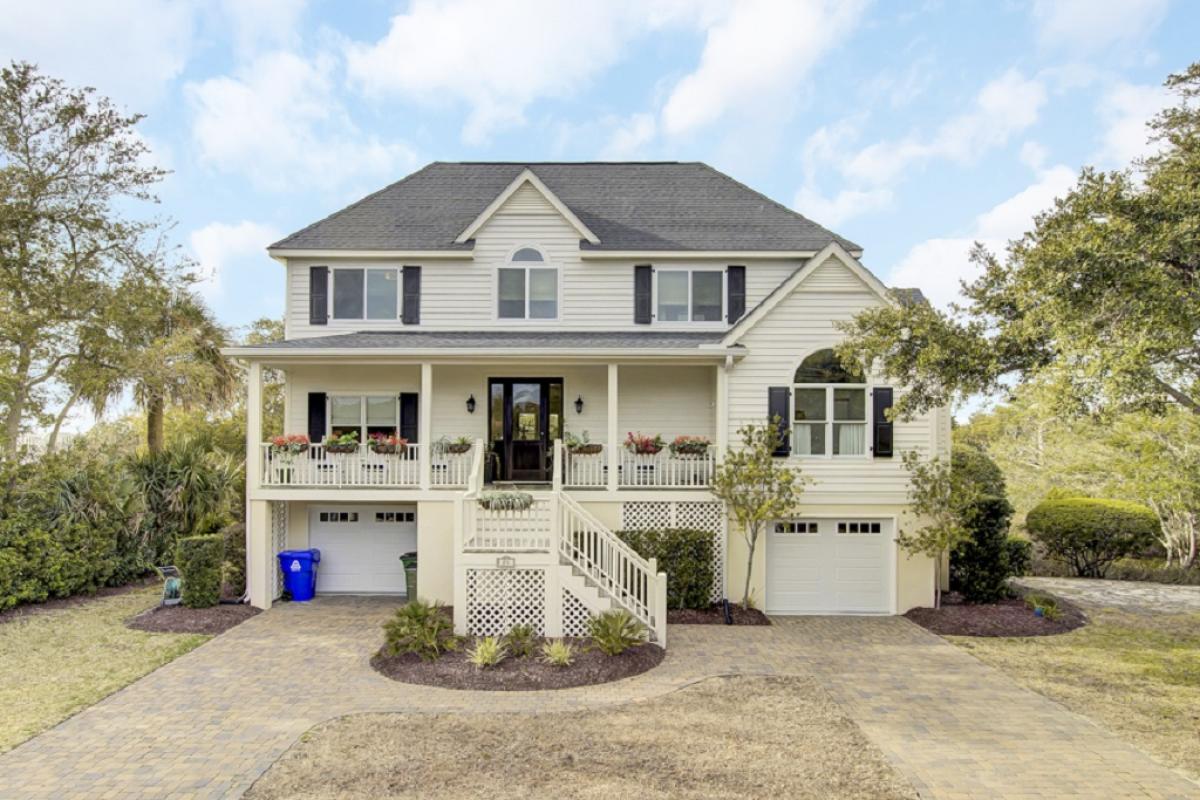 Charming elevated home with flower box windows, dual garages, and a welcoming central staircase.