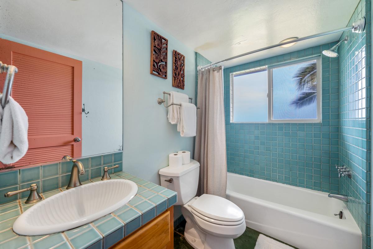 Refresh in your turquoise-tiled bathroom with tropical palm views and thoughtful touches like plush towels and decorative artwork.