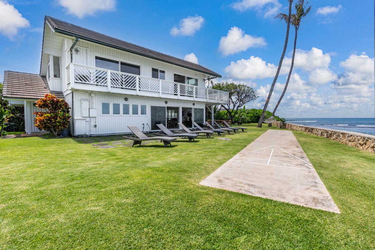 Stunning beachfront property with pristine lawn, palm trees, and direct ocean access for the ultimate tropical getaway.