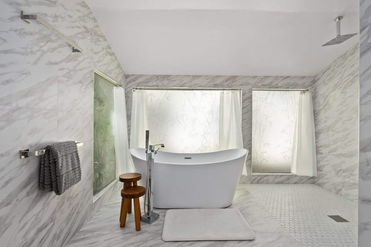 Soaking tub and rainfall shower set within a bright marble-lined sanctuary.