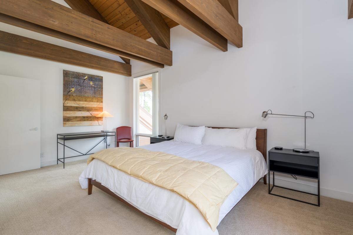 Unwind in your serene bedroom, where dramatic wood beams soar overhead and crisp linens invite restful nights. Natural light and minimalist design create a peaceful retreat perfect for recharging.