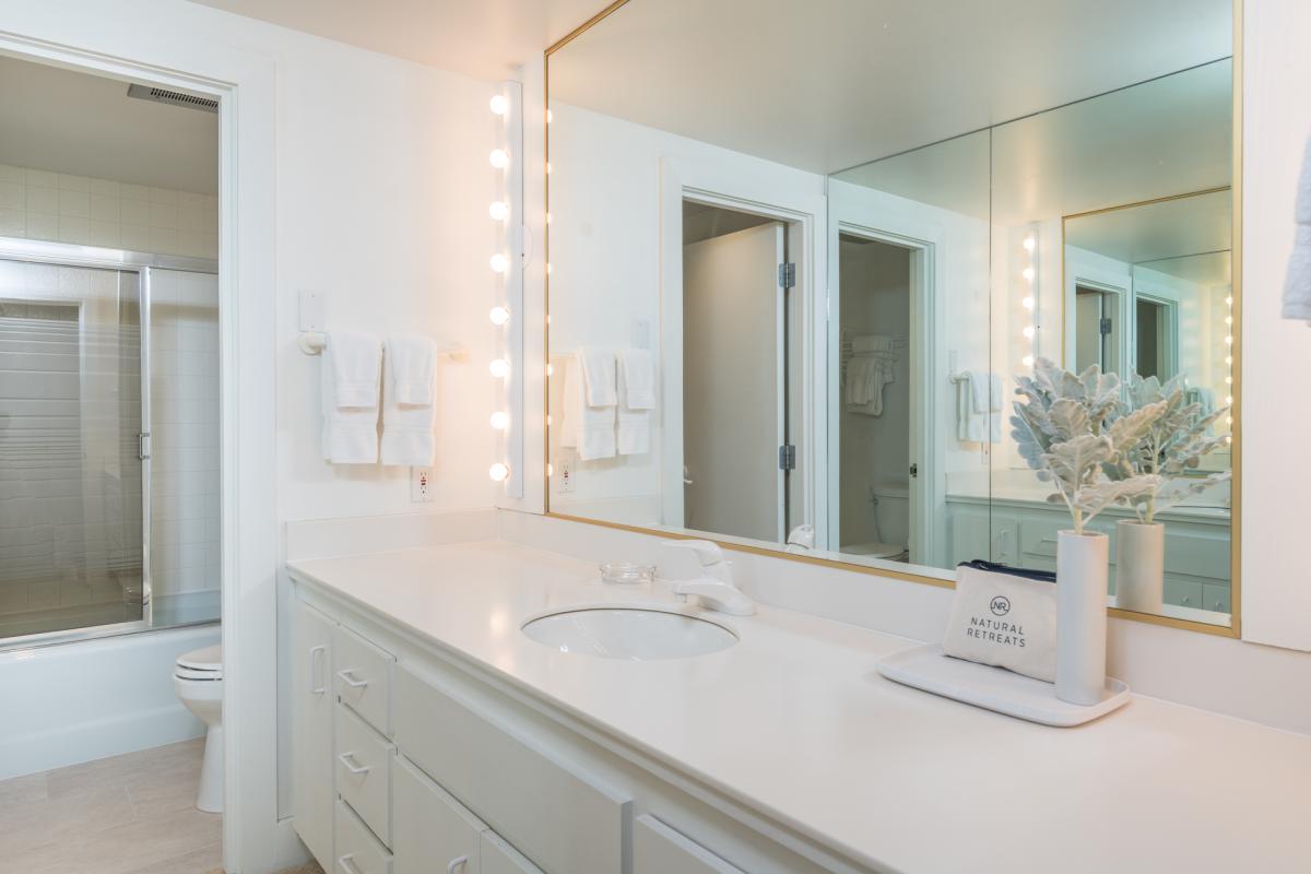 Step into your own serene spa retreat with this bright, beautifully lit bathroom featuring marble countertops, thoughtful coastal accents, and a spacious vanity to make your morning routine effortless.