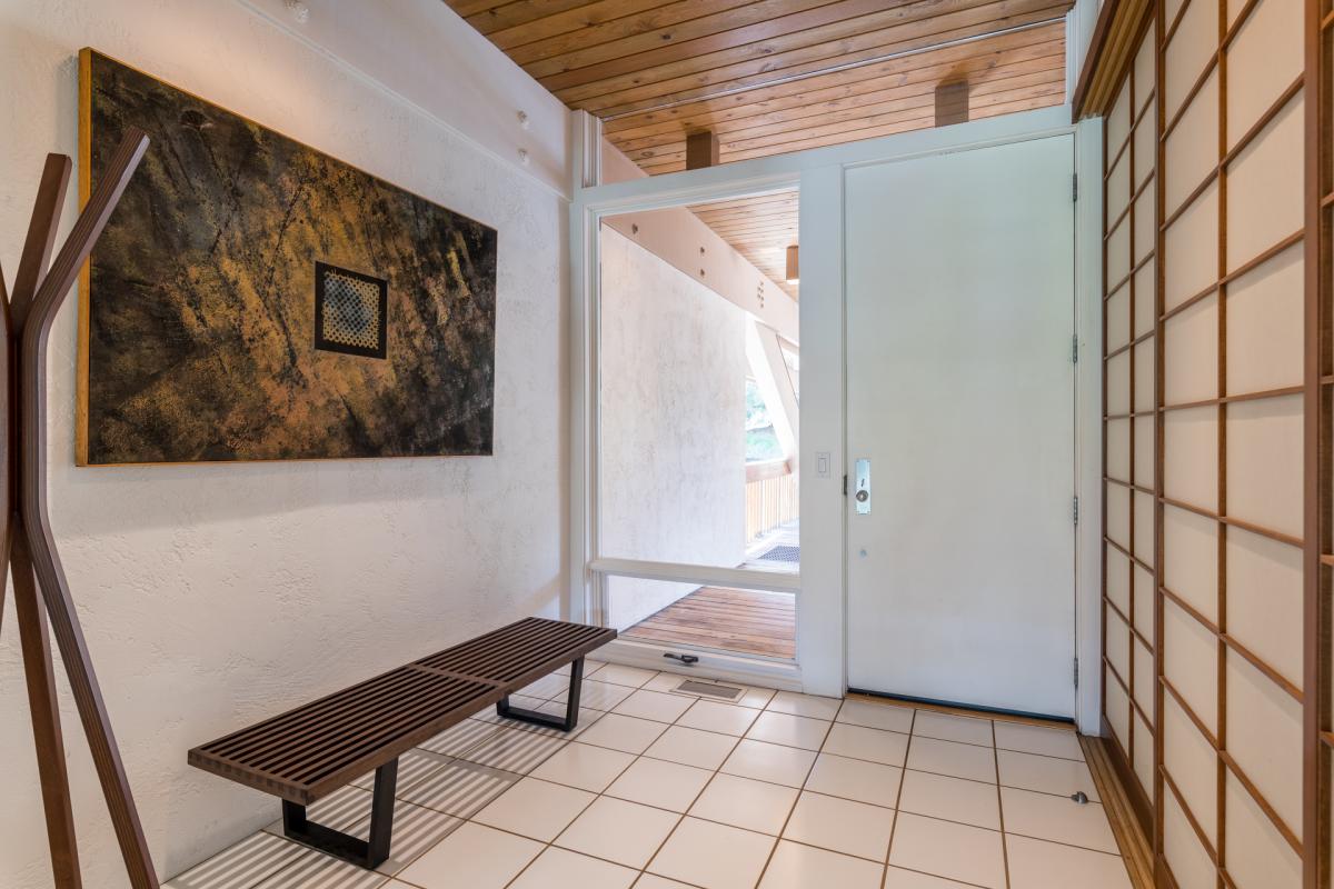 A serene entryway welcomes you with warm wood-paneled ceilings, elegant tile floors, and tasteful artwork that sets a relaxing tone from the moment you arrive.