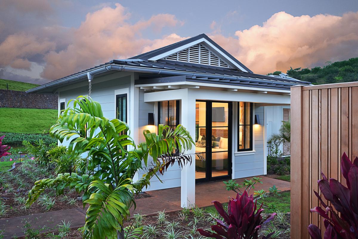 Tropical plantings frame the entry path, the home easing into its garden setting.
