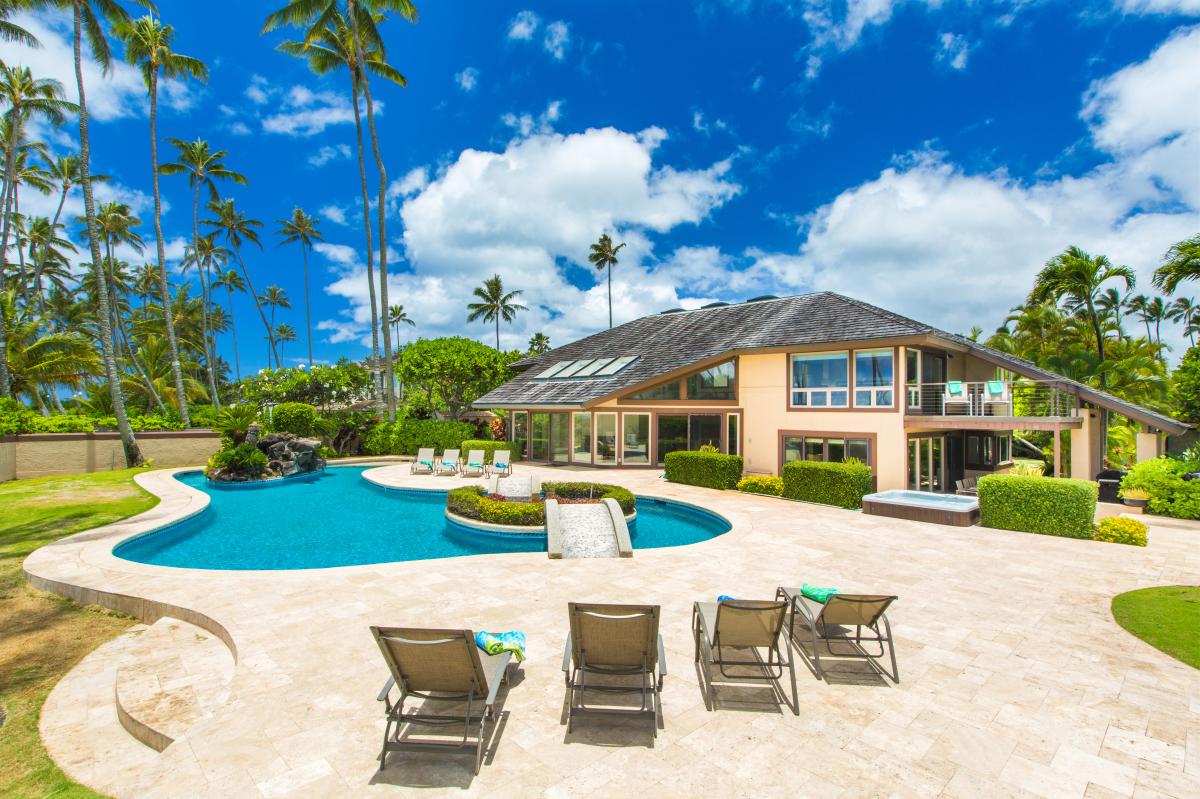 The whole estate at a glance: freeform pool, palm-lined lawn, and the Pacific just beyond.