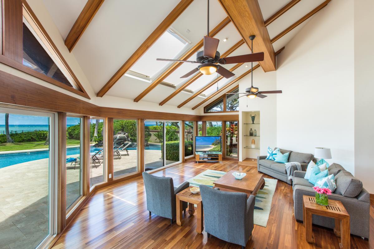 Vaulted open-beam ceilings rise over a living room that opens straight to the water.