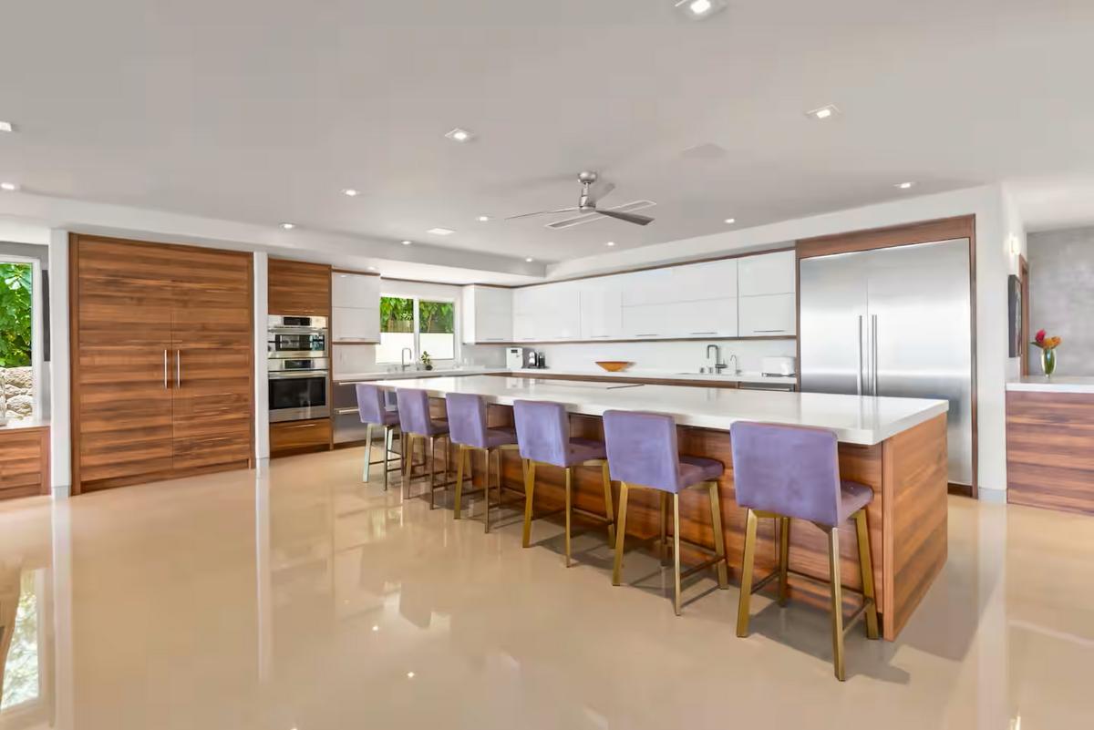 The main kitchen runs long, an island and a row of stools at its center.