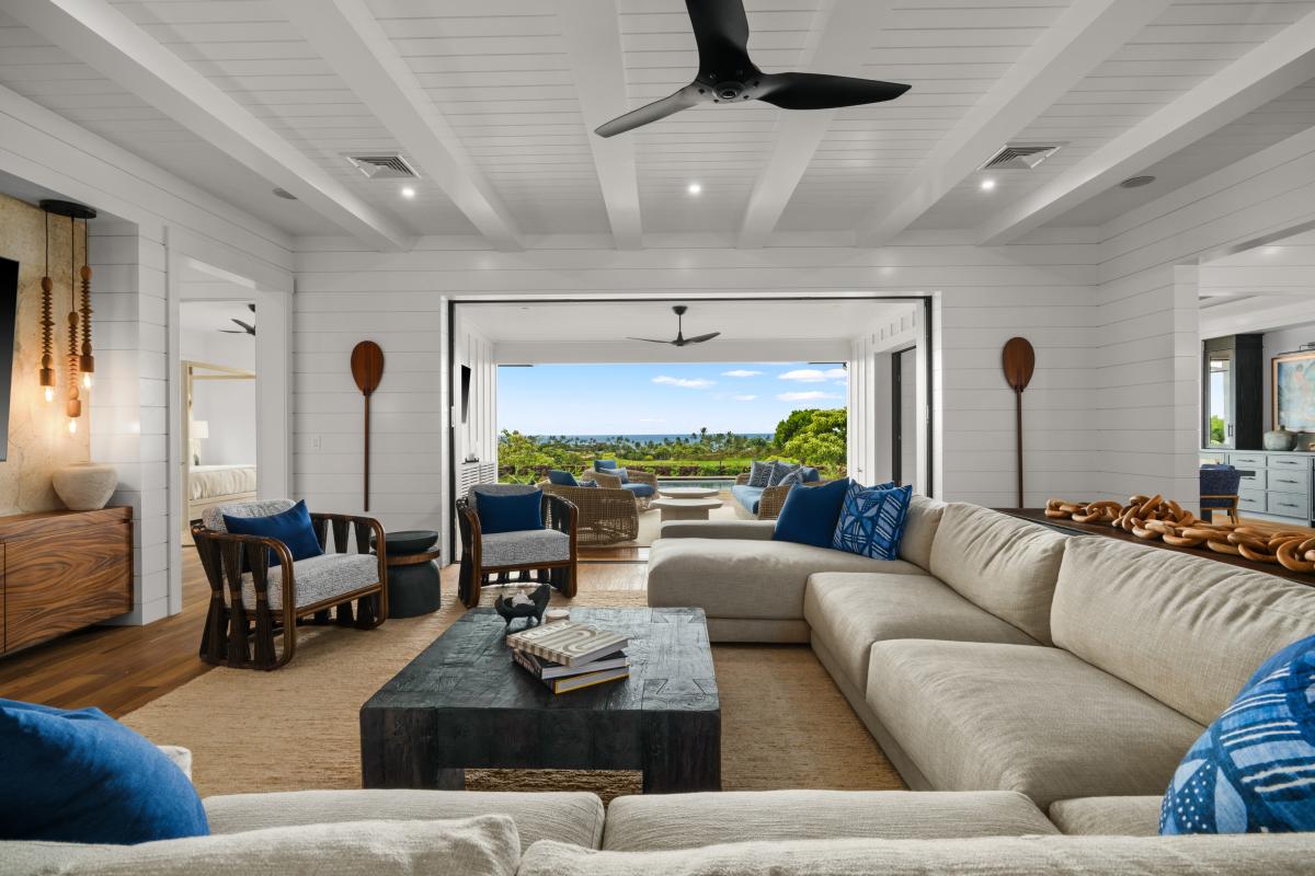 Afternoon light pools in the main room across a deep sectional and open doors.
