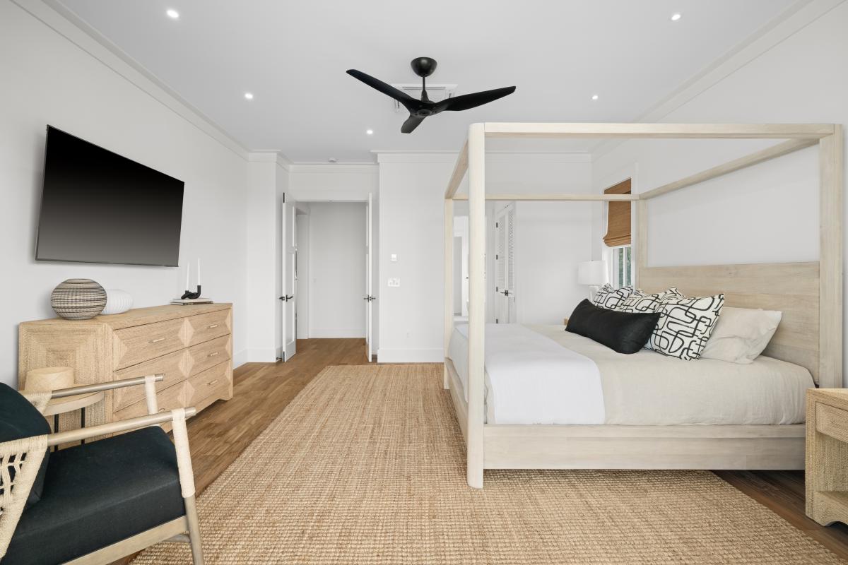 This bedroom keeps its own wall TV and dresser, bright and uncluttered.