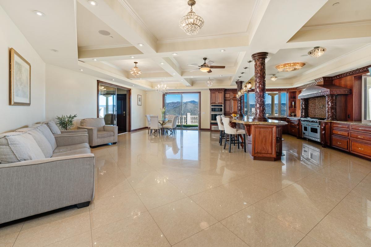 The great room holds it all, sofas at one end and hillside windows at the other.